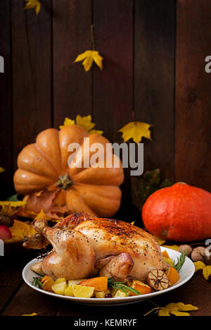 Roasted turkey garnished with cranberries on a rustic style table decorated with pumpkins, orange, apples and autumn leaf. Thanksgiving Day. Stock Photo
