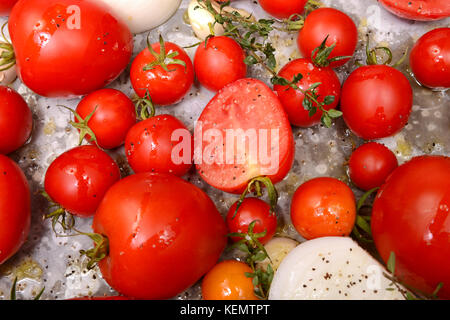 Fresh tomatoes, garlic, onions and thyme in roasting pan ready for roasting to make delicious tomato and basil soup Stock Photo