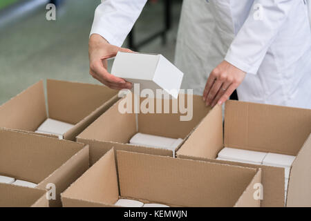 High-angle view of hands of worker putting packed products in ca Stock Photo