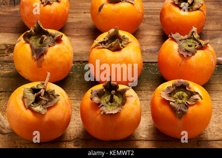 Colorful and fresh persimmons aligned on an old wooden table