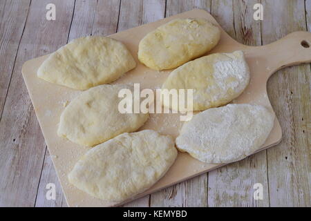 Homemade apple pies on a wooden cutting board ready to be baked.Step by step cooking Stock Photo