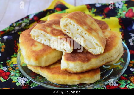Homemade apple pies on a glass plate on a multicolored cloth. Stock Photo