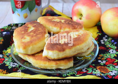 Homemade apple pies on a glass plate on a multicolored cloth. Stock Photo
