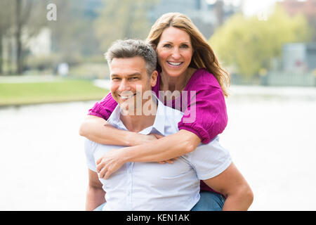 Portrait Of Happy Man Piggybacking His Wife Stock Photo
