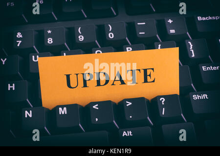 Yellow paper note on black keyboard with writing Update. Close up. Stock Photo