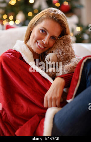 Young woman hugs teddy bear in Christmas eve Stock Photo