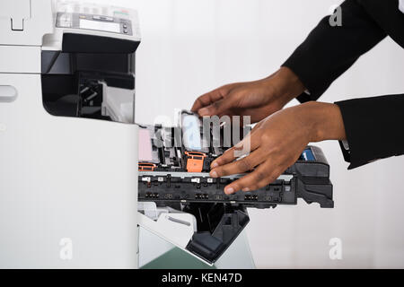 Close-up Of African Businesswoman Hand Fixing Photocopy Machine In Office Stock Photo