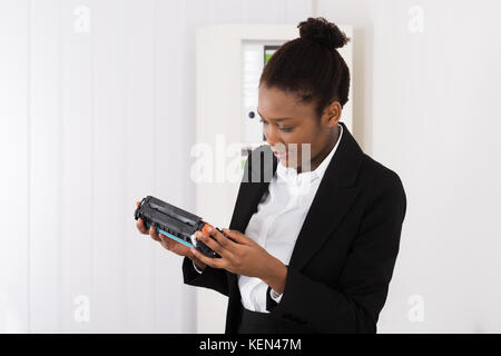 Young African Businesswoman Looking At Cartridge In Office Stock Photo