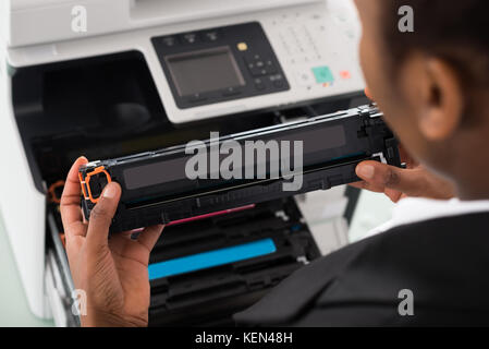 Young African Businesswoman Fixing Cartridge Near Photocopy Machine In Office Stock Photo