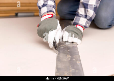 worker cutting plasterboard with construction knife. Attic renovation Stock Photo