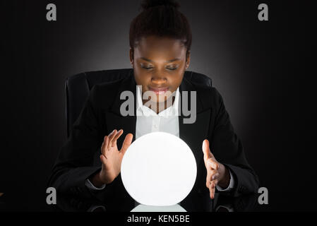 Young African Businesswoman Predicting Future With Crystal Ball On Desk ...