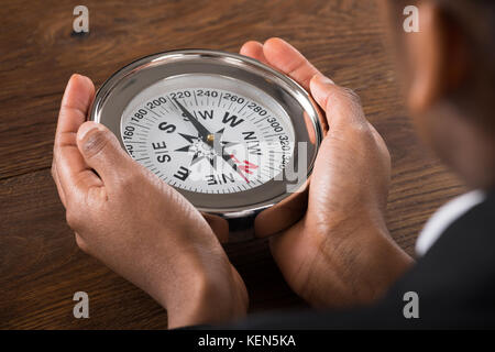 Close-up Of A Businessperson Hand Holding Compass On Desk Stock Photo