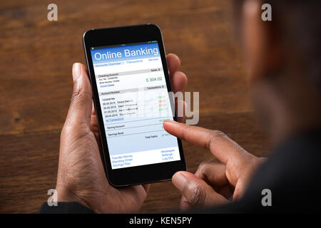 Close-up Of Young Businesswoman Using Online Banking On Mobile Phone In Office Stock Photo