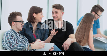 couple of University students sitting on a sofa with friends in  Stock Photo