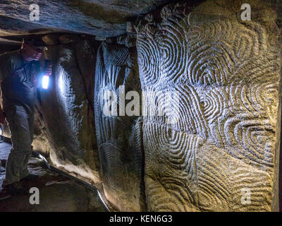 GAVRINIS CAVE  TOUR GUIDE TORCHLIGHT STONE CARVINGS TEXTURE INTERIOR Brittany France, prehistoric cairn, dolmen, dry stone grave, with renowned symbolic and mysterious Stone Age carvings. One of the most outstanding examples of earliest architecture in the Western World. Cairn de Gavrinis Sagemor Cale de Penn-Lannic, Larmor Baden Brittany France (Megalithes du Morbihan) Stock Photo