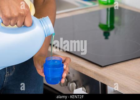 Close-up Of A Woman's Hand Pouring Detergent In The Blue Bottle Cap Stock Photo