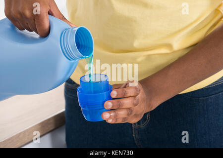 Close-up Of A Woman's Hand Pouring Detergent In The Blue Bottle Cap Stock Photo