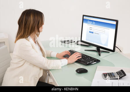 Happy Young Businesswoman Signing Into Website On Computer Stock Photo