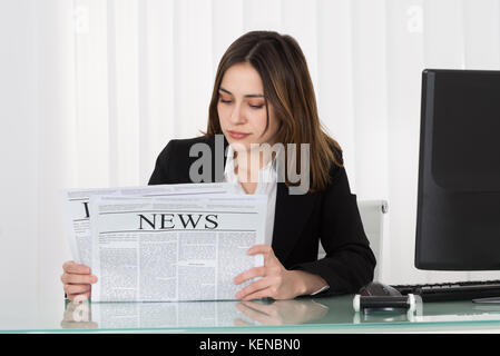 Photo Of Young Businesswoman Reading Newspaper In Office Stock Photo
