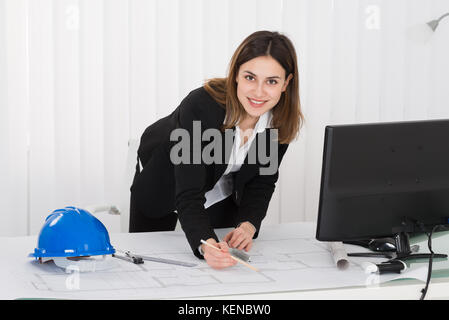Young Happy Female Architect Working On Blueprint In Office Stock Photo