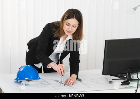 Young Happy Female Architect Working On Blueprint In Office Stock Photo