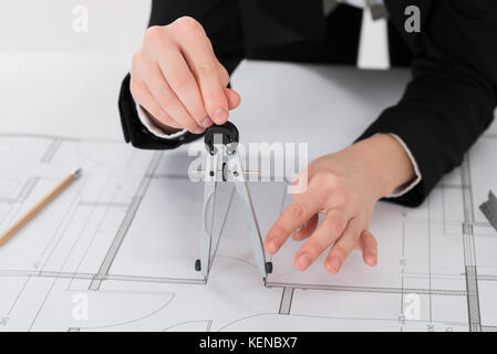 Close-up Of Female Architect Hands Holding Compass On Blueprint Stock Photo