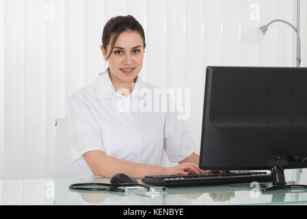 Young Female Doctor Working On Computer At Desk Stock Photo