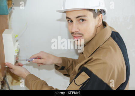 young electrician working on fuse board Stock Photo