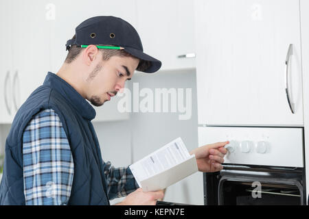young repairman in overall installing brand new oven in kitchen Stock Photo