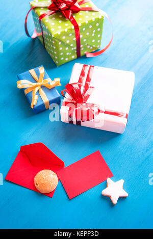 Vertical image with a bunch of multicolored presents, a red opened envelope with an empty card, gingerbread and delicious star shaped cookies. Stock Photo