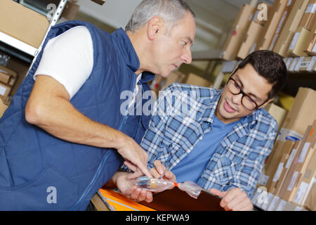 young and older worker chatting in warehouse Stock Photo
