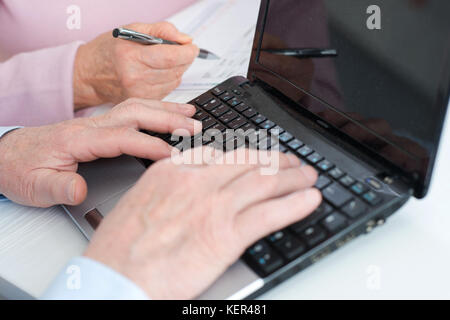 senior persons hands typing on computer Stock Photo