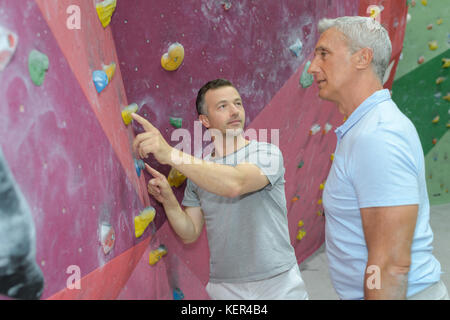 father and son perform climbing on vertical wall Stock Photo