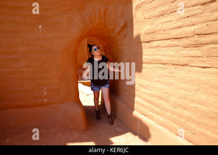 A young woman looks with wonder going through a passage in the ruins of an old Mission at Pecos National Historic Park near Santa Fe, New Mexico. Stock Photo