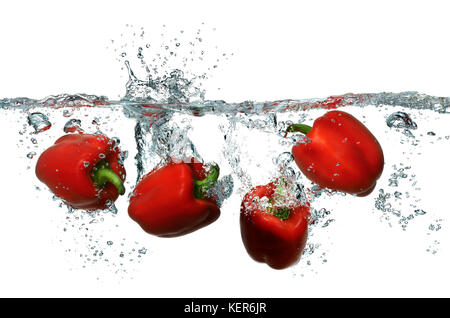 Bright red bell peppers splashing into fresh clean water Stock Photo