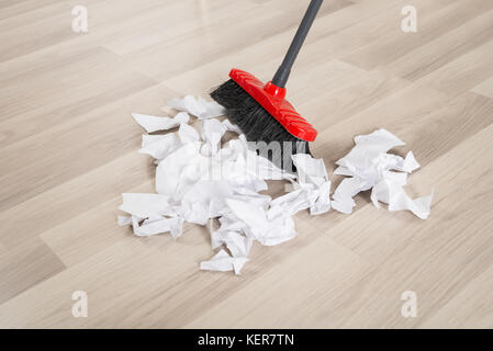 Broom With Torn White Papers On Hardwood Floor Stock Photo