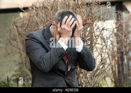 Mature Businessman In Depression With Hands On Forehead Stock Photo
