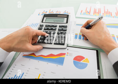 Close-up Of Businessman Analyzing Graph And Using Calculator Stock Photo
