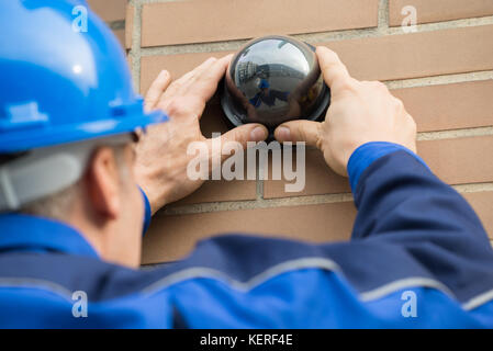 Close-up Of A Mature Male Technician Installing Camera In Building Stock Photo
