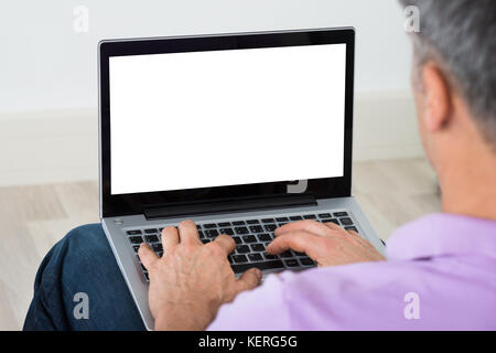 Close-up Of Mature Man Using Blank Screen Laptop At Home Stock Photo