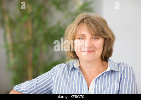 Portrait of smiling blonde middle age woman in the room Stock Photo