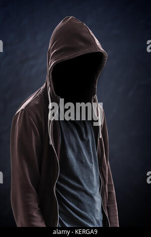 Silhouette of man with a hood and face in the dark, black background with copy space, criminal or hacker concept Stock Photo