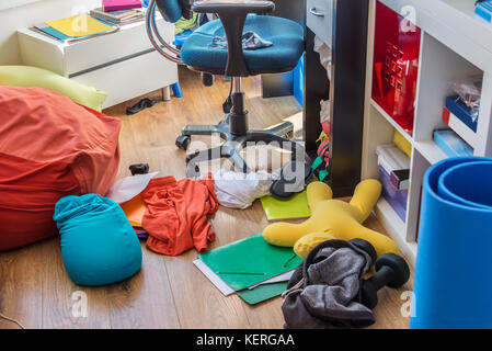 Boy messy bedroom with clothes and colorful pillows on the floor Stock Photo