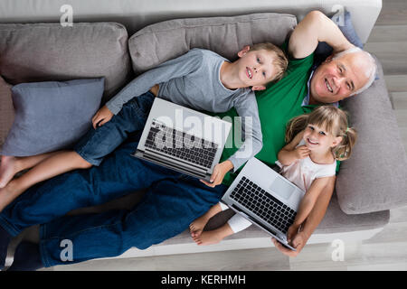 High Angle View Of Grandfather With Kids And Laptop Computers At Home Stock Photo