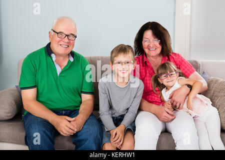 Happy Family Wearing Glasses While Sitting On Couch Together At Home Stock Photo
