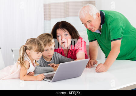 Happy Family Using Laptop Computer With Kids To Browse Internet Stock Photo