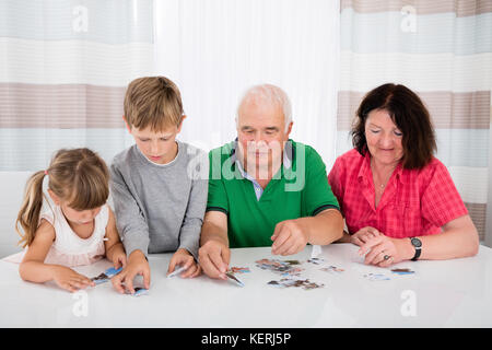 Family Holding Jigsaw Puzzle Pieces While Playing Game Stock Photo