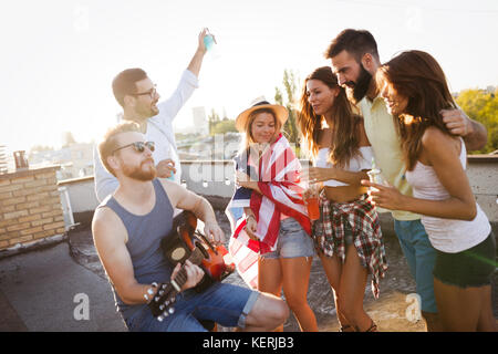 Group of happy friends having party on rooftop Stock Photo