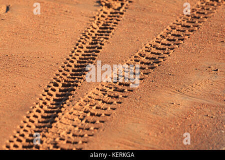 Traces of tire treads on orange sand, diverging in different directions. Stock Photo