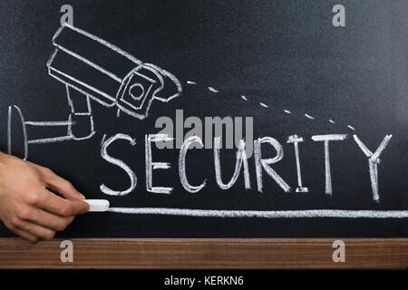 Close-up Of A Person Hand Showing Security Concept On Blackboard Stock Photo